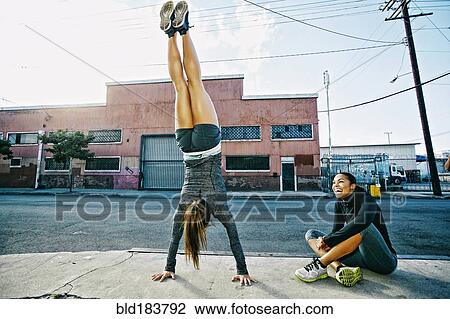 Stock Image - Athlete doing handstand on sidewalk. Fotosearch