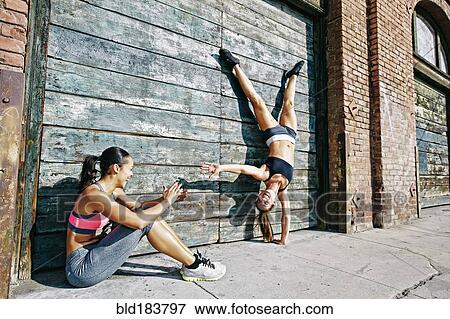 Stock Photo - Athlete doing handstand on sidewalk. Fotosearch