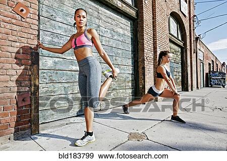 Athletes stretching on sidewalk View Large Photo Image Stock Photo - Athletes stretching on sidewalk. Fotosearch