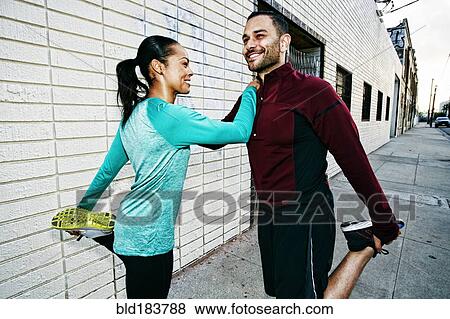 Athletic couple stretching on sidewalk View Large Photo Image Stock Photo - Athletic couple stretching on sidewalk. Fotosearch