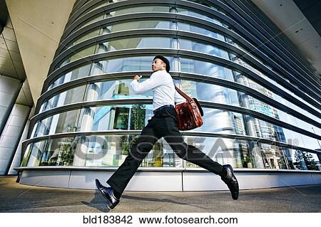 Stock Image - Black businessman running outside office building. Fotosearch