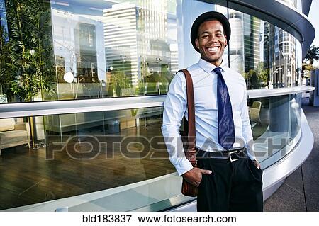 Black businessman smiling outside office building View Large Photo Image Stock Photo - Black businessman smiling outside office building. Fotosearch
