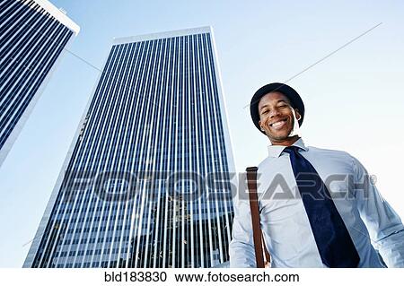 Black businessman smiling under highrise buildings View Large Photo Image Stock Image - Black businessman smiling under highrise buildings. Fotosearch