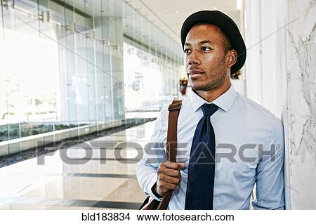 Black businessman standing in office lobby View Large Photo Image Picture - Black businessman standing in office lobby. Fotosearch