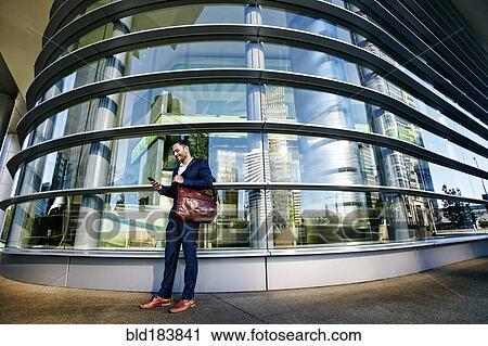Black businessman using cell phone outside office building View Large Photo Image Stock Image - Black businessman using cell phone outside office building. Fotosearch
