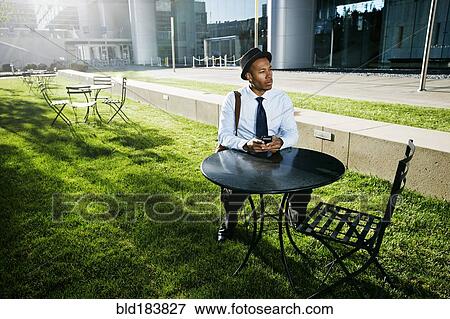 Stock Photo - Black businessman using cell phone outdoors. Fotosearch