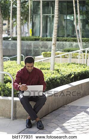 Black businessman using laptop outdoors View Large Photo Image Stock Image - Black businessman using laptop outdoors. Fotosearch