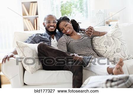 Stock Photo - Black couple smiling on sofa. Fotosearch