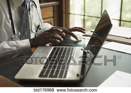 Stock Photo - Black doctor using digital tablet in office. Fotosearch