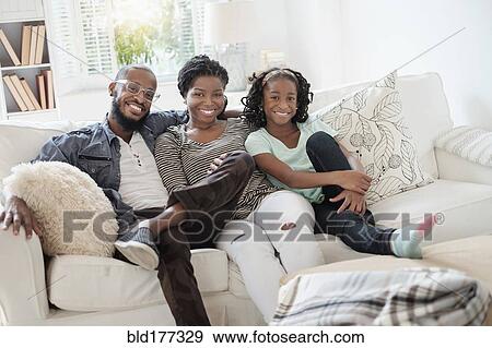 Stock Photo - Black family smiling on sofa. Fotosearch