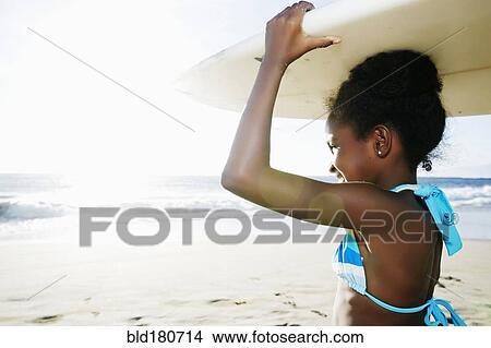 Black girl carrying surfboard on beach View Large Photo Image Picture - Black girl carrying surfboard on beach. Fotosearch