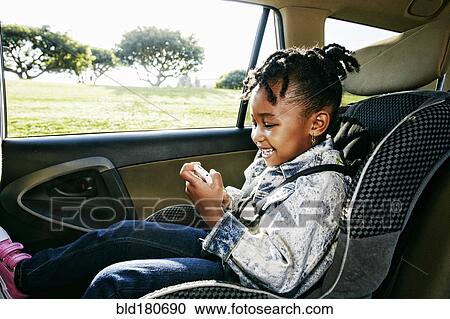 Stock Image - Black girl sitting in car seat. Fotosearch