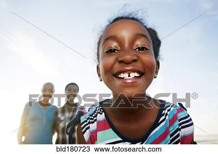 Stock Image - Black girl smiling outdoors. Fotosearch