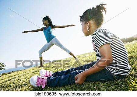 Stock Photography - Black girl watching mother practicing yoga. Fotosearch