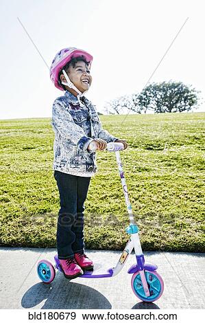 Stock Photo - Black girl wearing helmet on scooter. Fotosearch