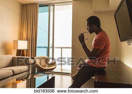 Black man leaning on credenza in living room View Large Photo Image Stock Photograph - Black man leaning on credenza in living room. Fotosearch