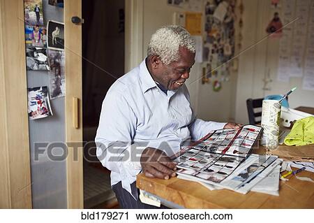 Stock Image - Black man reading magazine at table. Fotosearch