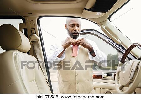 Black man tying bow tie in car View Large Photo Image Stock Photograph - Black man tying bow tie in car. Fotosearch