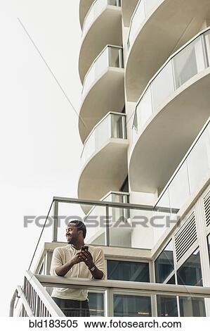 Black man using cell phone on balcony View Large Photo Image Stock Photography - Black man using cell phone on balcony. Fotosearch
