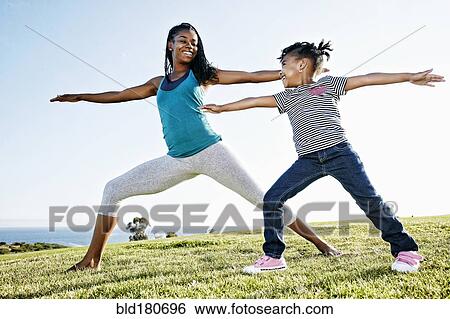 Stock Photograph - Black mother and daughter practicing yoga. Fotosearch