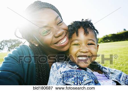 Stock Photo - Black mother and daughter smiling outdoors. Fotosearch