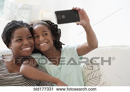 Stock Image - Black mother and daughter taking selfie. Fotosearch
