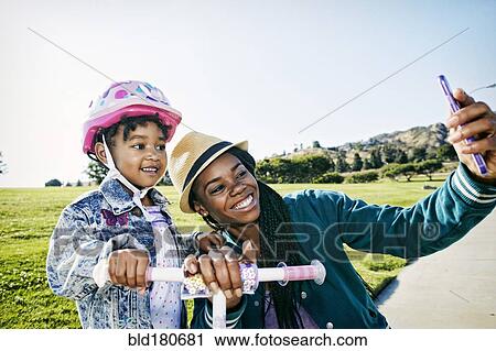 Stock Image - Black mother and daughter taking selfie. Fotosearch