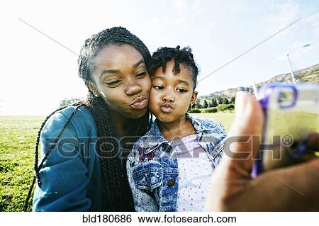 Black mother and daughter taking selfie outdoors View Large Photo Image Stock Photograph - Black mother and daughter taking selfie outdoors. Fotosearch