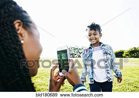 Black mother photographing daughter outdoors View Large Photo Image Stock Photo - Black mother photographing daughter outdoors. Fotosearch