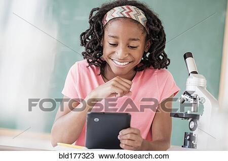 Stock Image - Black student using digital tablet in science class. Fotosearch