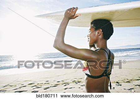 Black woman balancing surfboard on head at beach View Large Photo Image Stock Image - Black woman balancing surfboard on head at beach. Fotosearch