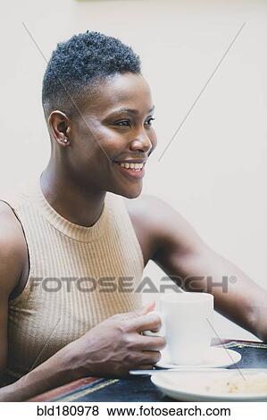 Stock Photo - Black woman drinking coffee in cafe. Fotosearch