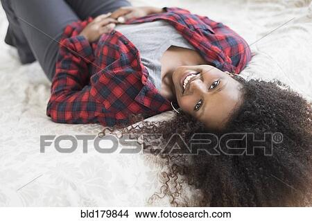 Picture - Black woman laying on bed. Fotosearch