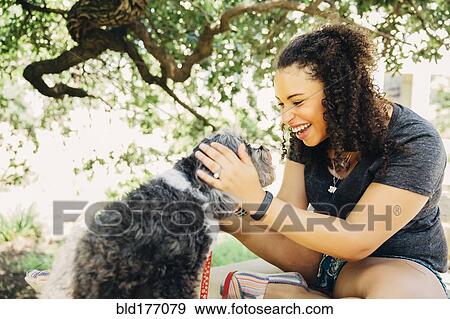 Stock Photo - Black woman petting dog outdoors. Fotosearch
