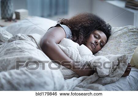 Stock Photograph - Black woman sleeping in bed. Fotosearch