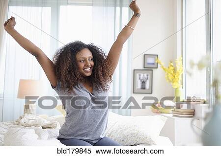 Stock Photography - Black woman stretching on bed. Fotosearch