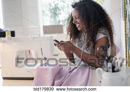 Black woman using cell phone at sewing machine View Large Photo Image Stock Photo - Black woman using cell phone at sewing machine. Fotosearch