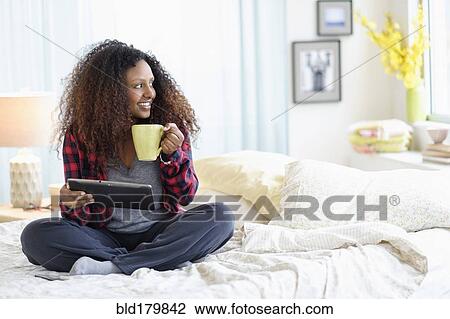 Black woman using digital tablet on bed View Large Photo Image Stock Image - Black woman using digital tablet on bed. Fotosearch
