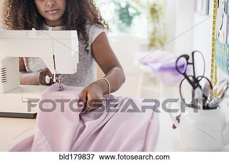 Stock Photo - Black woman using sewing machine. Fotosearch