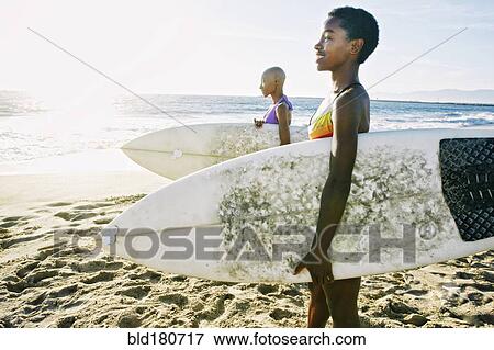 Black women carrying surfboards on beach View Large Photo Image Stock Photo - Black women carrying surfboards on beach. Fotosearch