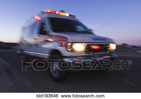 Stock Photograph - Blurred view of ambulance driving at dusk. Fotosearch