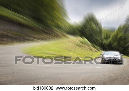 Stock Image - Blurred view of car driving on curved road. Fotosearch