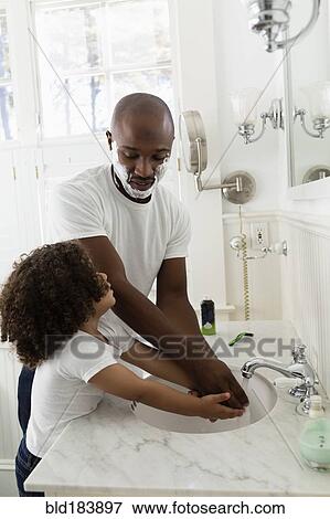 Stock Photo - Boy helping father shave in bathroom. Fotosearch