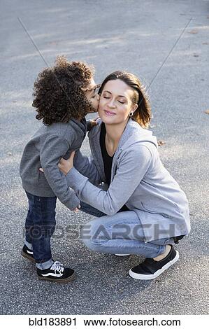 Boy kissing cheek of mother outdoors View Large Photo Image Stock Image - Boy kissing cheek of mother outdoors. Fotosearch