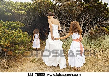 Stock Photo - Bride and flower girls walking on dirt path. Fotosearch