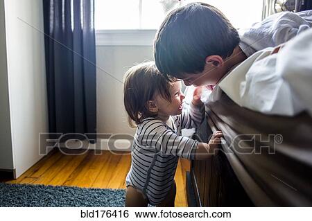 Stock Photograph - Brother and sister laughing on bed. Fotosearch
