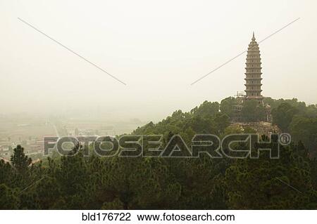 Stock Image - Buddhist temple tower on hilltop in remote landscape. Fotosearch