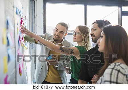 Stock Photo - Business people using adhesive notes in office. Fotosearch