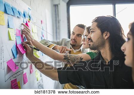Business people using adhesive notes in office View Large Photo Image Stock Photo - Business people using adhesive notes in office. Fotosearch