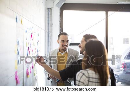 Business people using adhesive notes in office View Large Photo Image Stock Photography - Business people using adhesive notes in office. Fotosearch